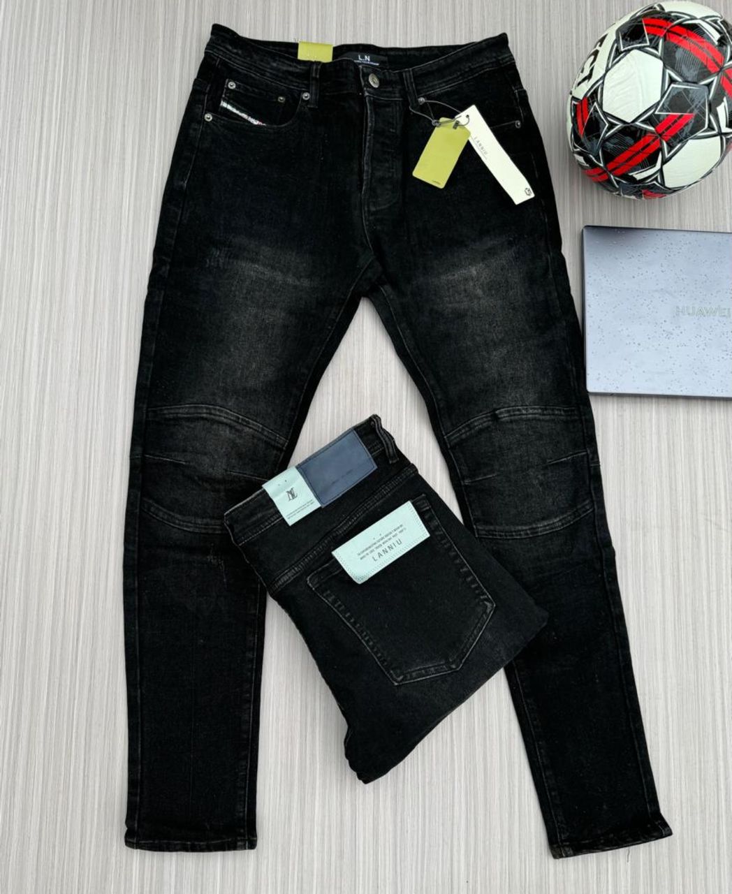 Black slim-fit denim jeans with subtle fading, displayed with a folded pair of jeans.