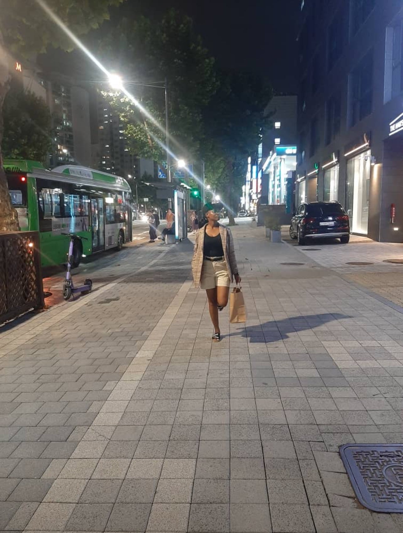 Female customer holding a shopping bag while posing in street lights